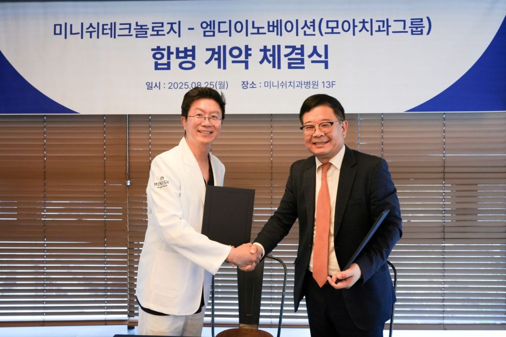 미니쉬테크놀로지와 엠디이노베이션의 합병 계약 체결식에서 두 관계자가 서명 후握手을 나누고 있는 모습.